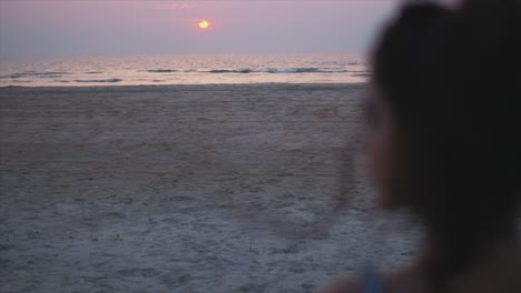 la mujer está sentada sola y disfrutando de la colorida puesta de sol sobre el mar