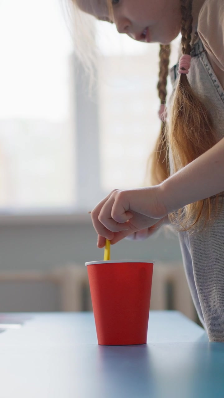 Young Girl Sorting Colorful Crayons into a Red Paper Cup