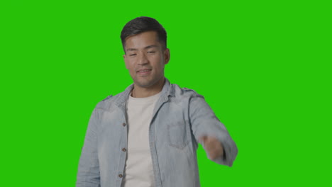 studio shot of casually dressed young man giving thumbs up gesture against green screen 2