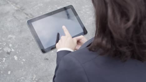 two female colleagues using tablet and watching content together while walking outside