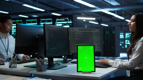 software developer in data center monitoring security threats using mockup tablet