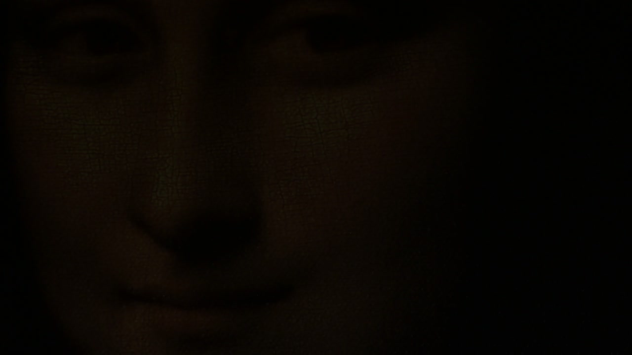 Face of Gioconda o Mona Lisa illuminated with lights of candles fading to black