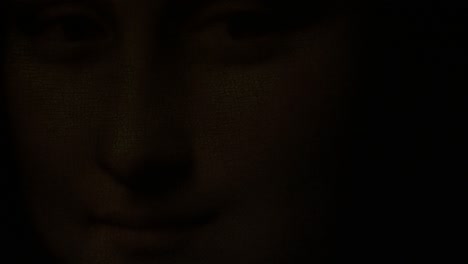 face of gioconda o mona lisa illuminated with lights of candles fading to black