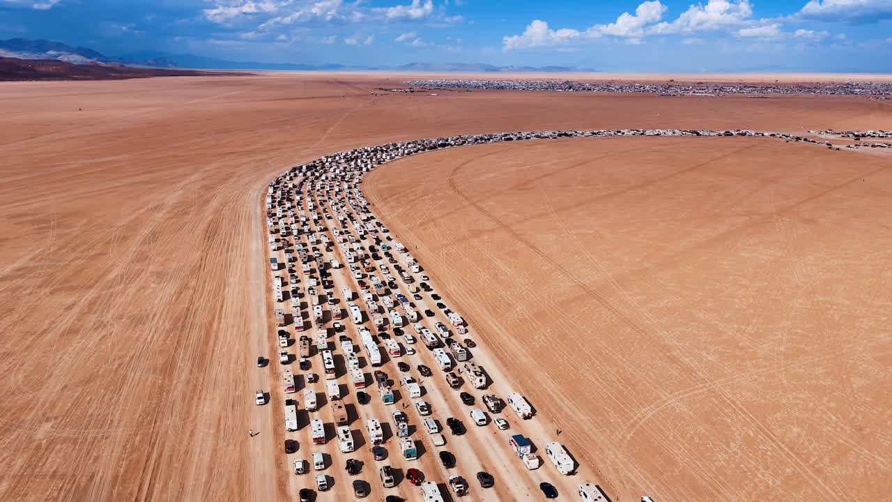 Striking number of cars and campervans standing in a row among the desert. Transport waiting its turn to the camp in Black Rock Desert for Burning man festival. Aerial view