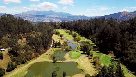 rising aerial view of golf course between a forest and mountains in ecuador