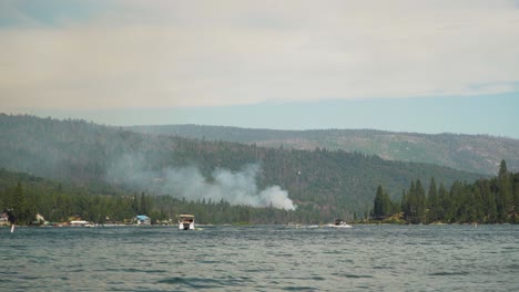 incendio forestal de california, quemaduras de montaña en el borde del lago, helicóptero arroja agua sobre una columna de humo