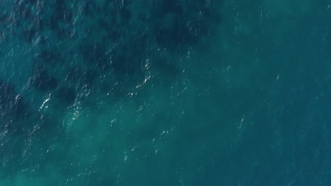 Aerial-View-Of-Wavy-Blue-Ocean-With-Visible-Coral-Reefs-In-An-island-In-Philippines