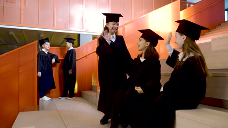 estudiantes de kindergarten felices con toga y birrete jugando y hablando juntos antes de la ceremonia de graduación de preescolar