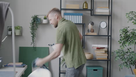 man putting laundry into laundry basket in a living room