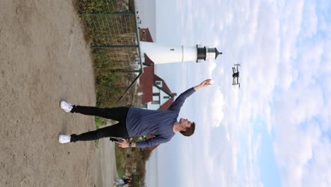 vertical - man flying drone with portland head light lighthouse in background