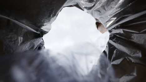 slow motion low angle view of man tossing plastic bottle into recycling trash container