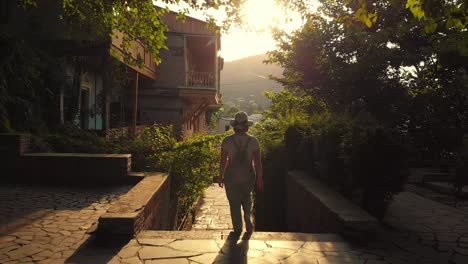 adult girl is walking by ancient street of tbilisi, georgia. cinematic mood at sunset. slow motion