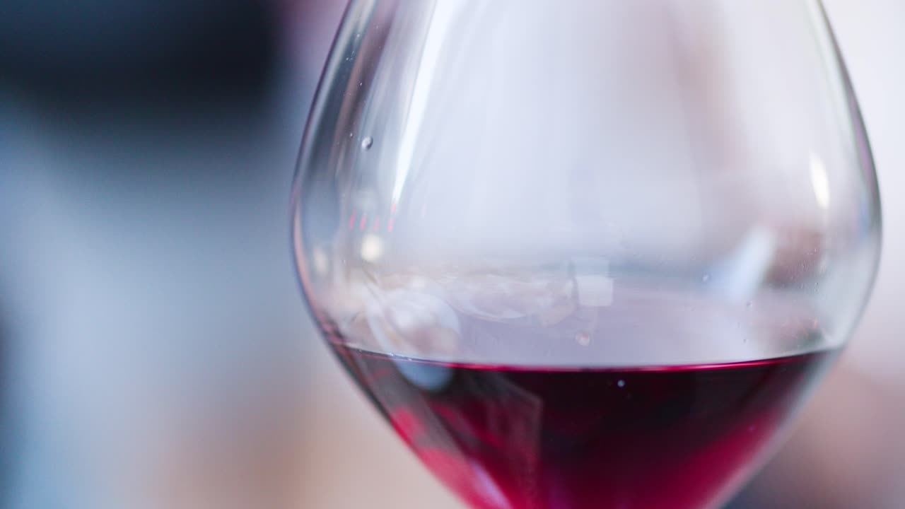 Bicchiere di vino rosso a fuoco, ambiente minimalista esterno, sfondo bokeh delicato, movimento leggero della fotocamera