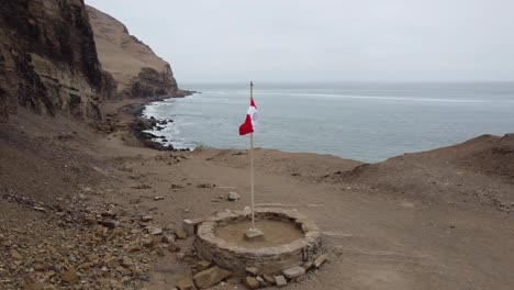 drone video orbiting around a peruvian flag on a cliff side path next the ocean coast