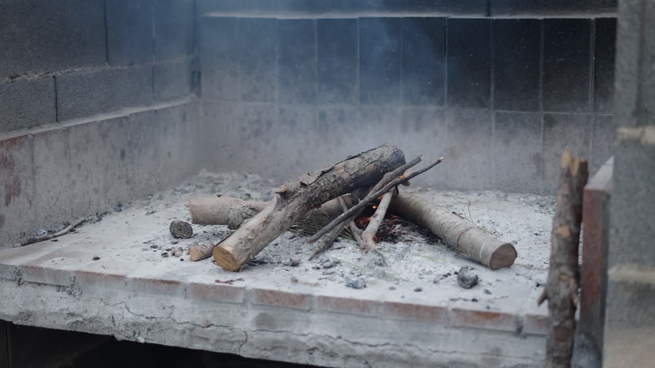 Small wood fire burning in a concrete barbecue or fireplace