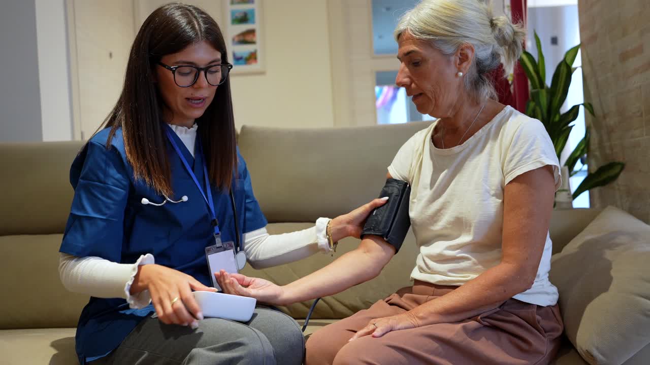 Doctor checking blood pressure of a senior woman at home