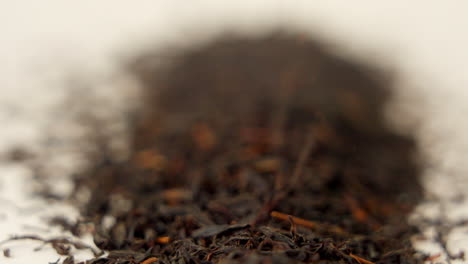 macro shot of black tea falling on white ground in 100 fps