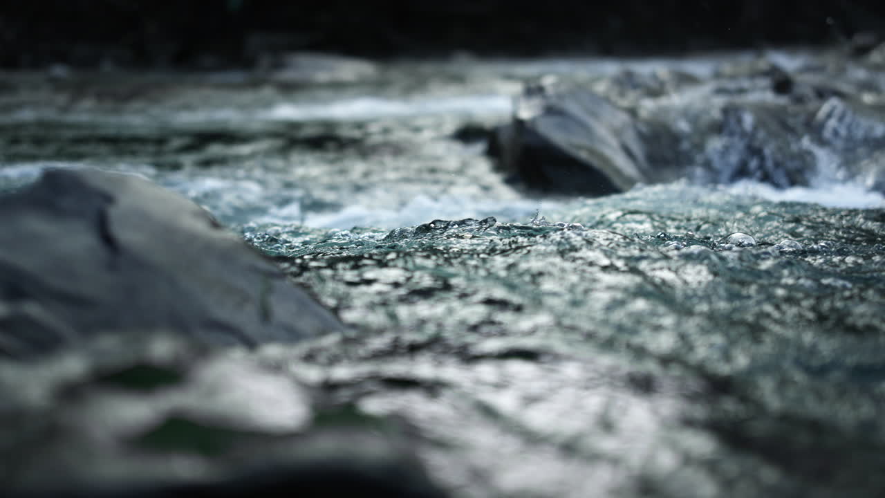 Clean stream flowing at stone rapids. Mountain river rushing in rocky landscape.