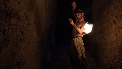 cinematic shot of a fire performer juggling fire balls in a dark cave