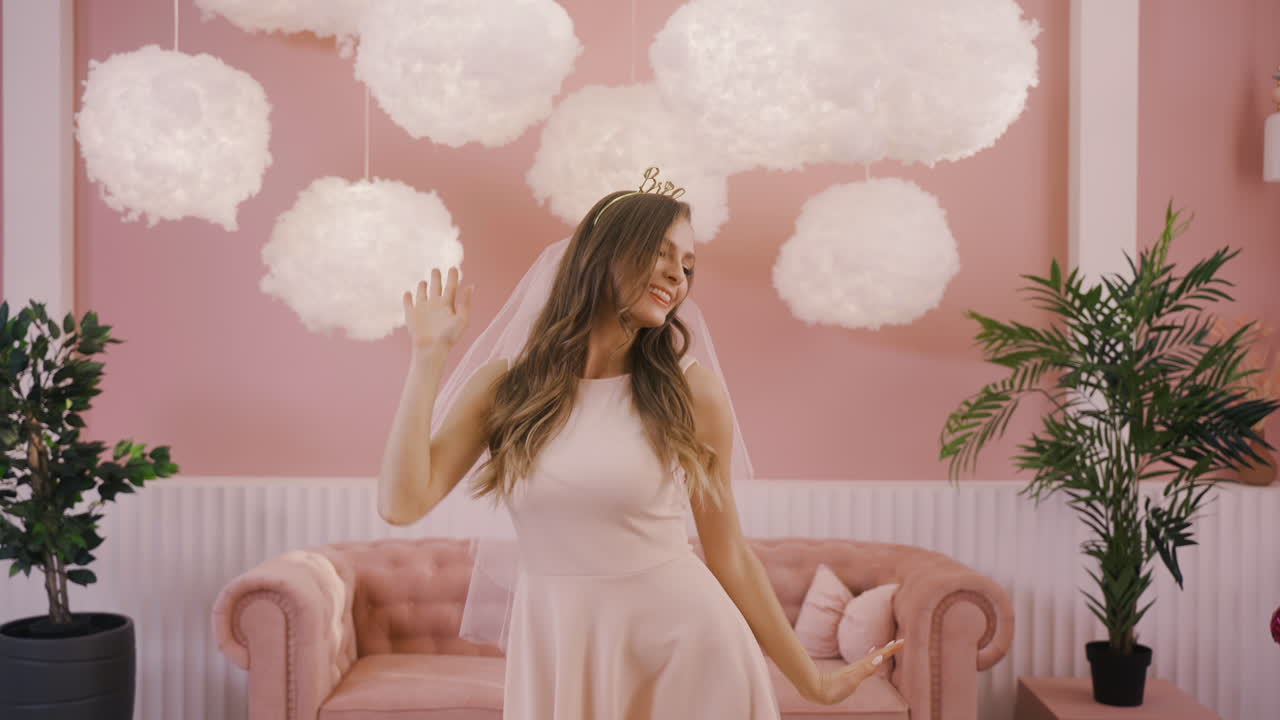 카메라 앞에서 머리 장식과 베일 춤을 추는 행복한 총각 소녀의 전면 모습