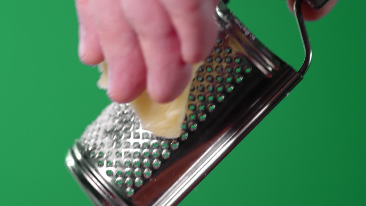 Male hand rubbed Parmesan cheese on a grater.