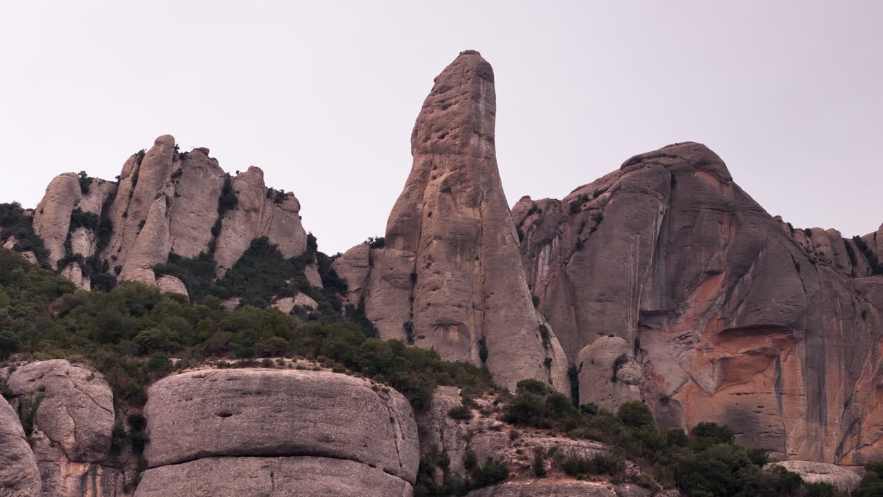 드론 크레인 다운 은 조용한 흐린 날을 배경으로 몬세라트의 둥근 절벽 꼭대기를 우아하게 드러니다.