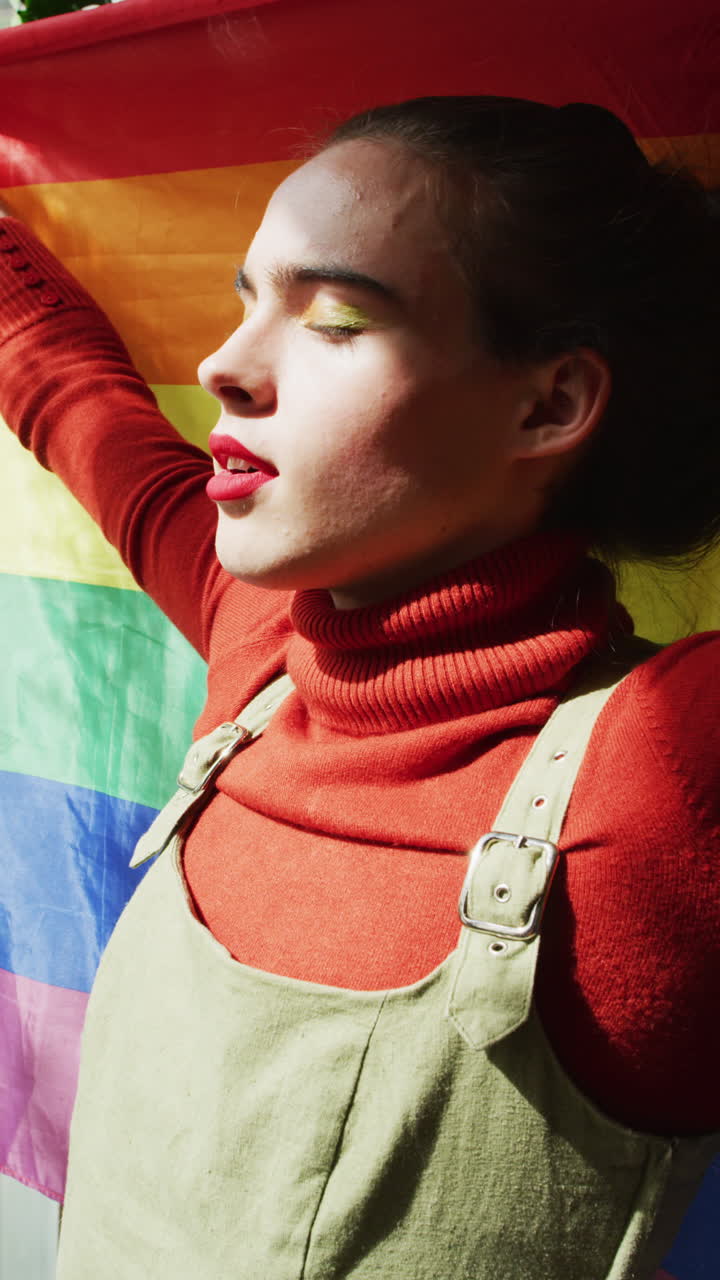 video vertical de una mujer transgénero caucásica no binaria sosteniendo una bandera lgbt