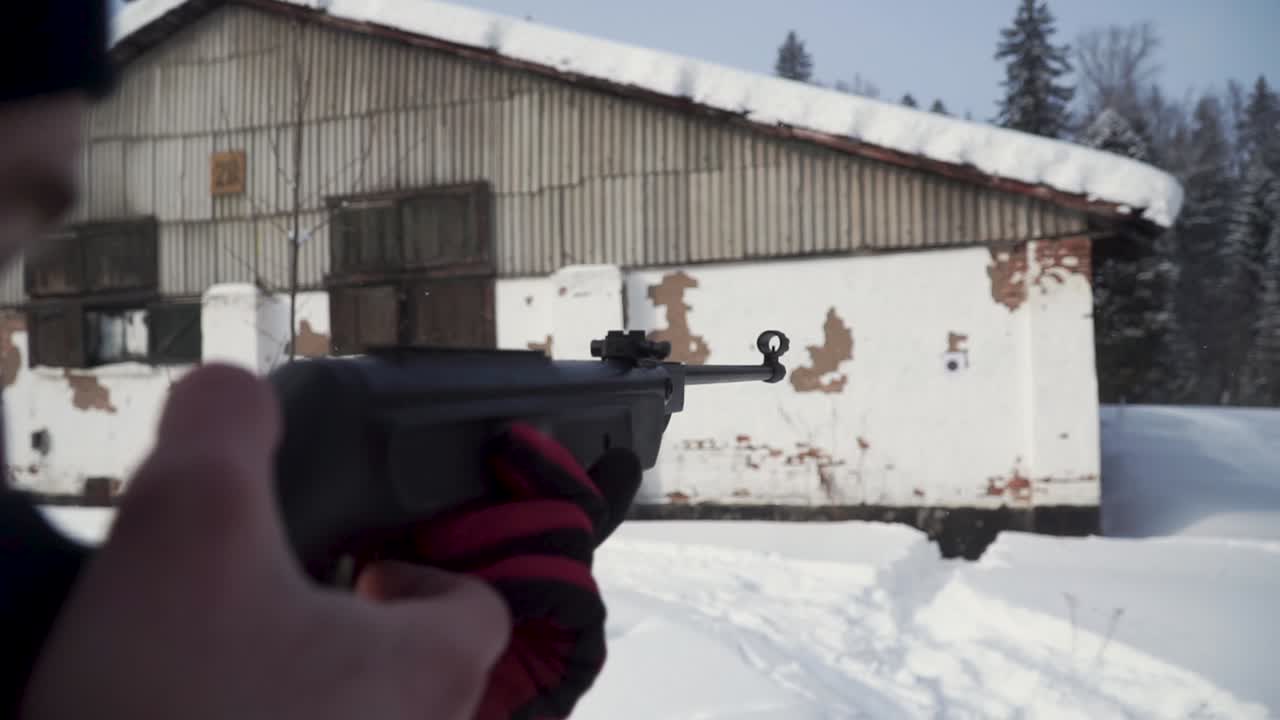 persona disparando un rifle airsoft en invierno