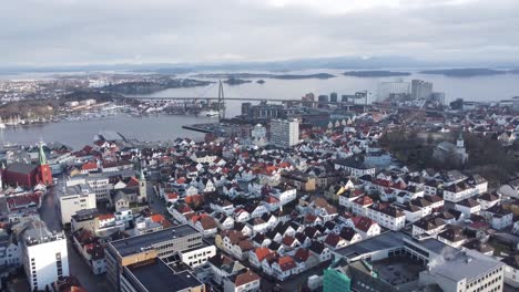 Flying-over-Stavanger-urban-city-centre-and-towards-the-city-bridge---Vassoy-ferry-passing-under-bridge---Norway-Aerial