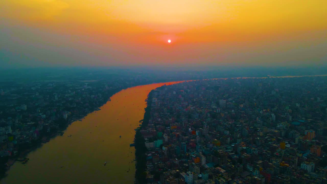 Vista aerea sul paesaggio urbano affollato lungo il fiume di Dhaka, sul fiume Buriganga, sotto l'atmosfera colorata e inquinata del Bangladesh.