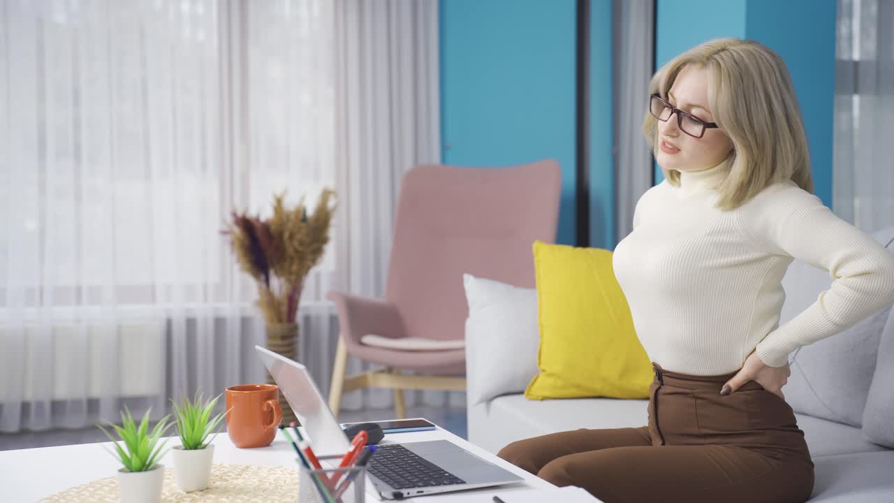 집에서 일하는 젊은 여성은 피곤하고 느슨하고 허리 통증이 있습니다.