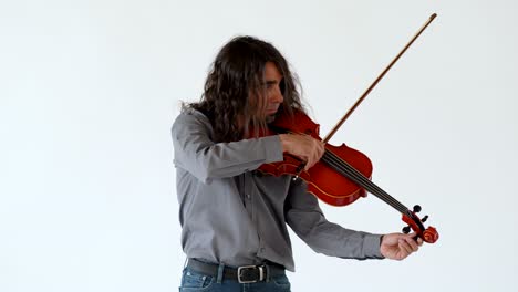 Tiro-Medio-De-Un-Músico-Latino-De-Pelo-Largo-Con-Camisa-Gris-Y-Jeans-Afinando-Una-Viola-Roja-Sobre-Fondo-Blanco