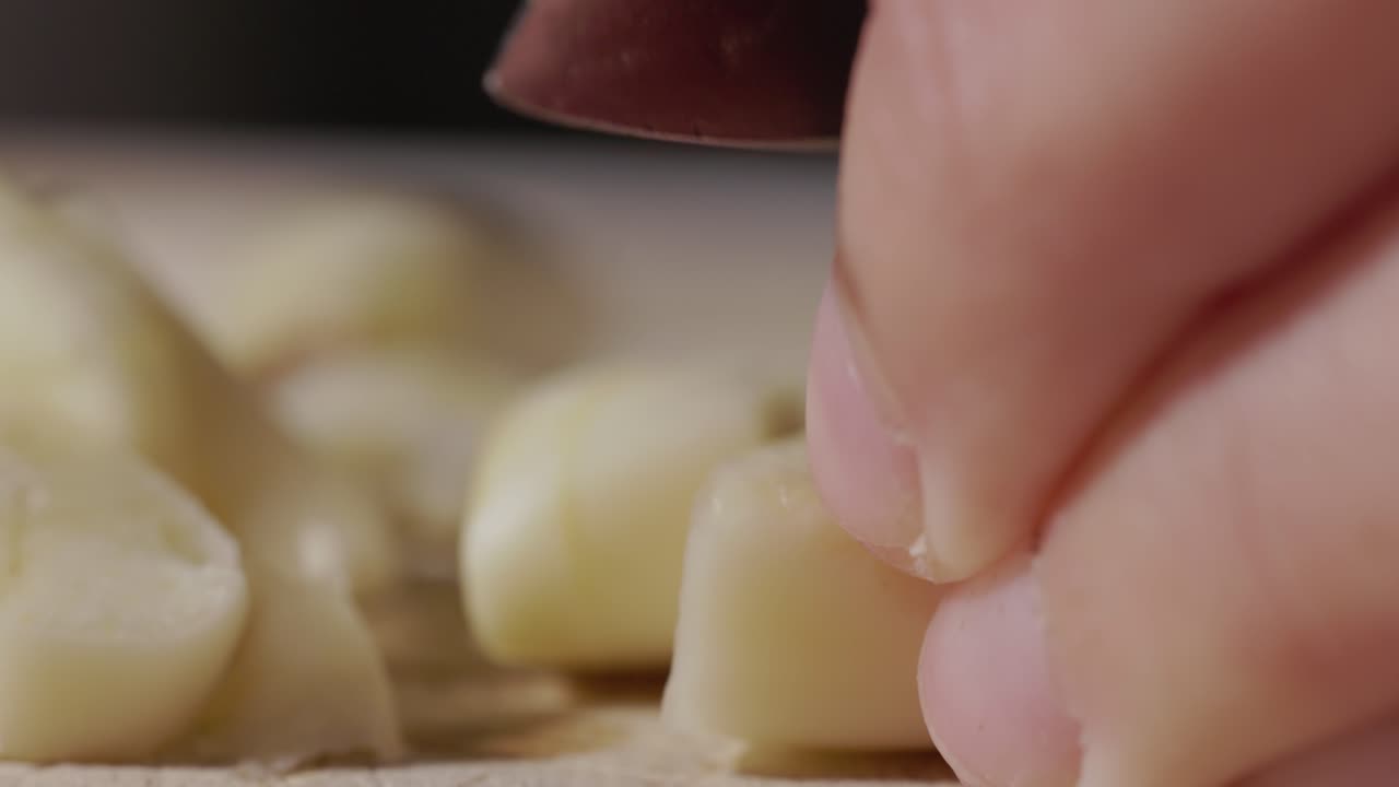 Chef's Hand Cutting Fresh Peeled Garlic With A Knife
