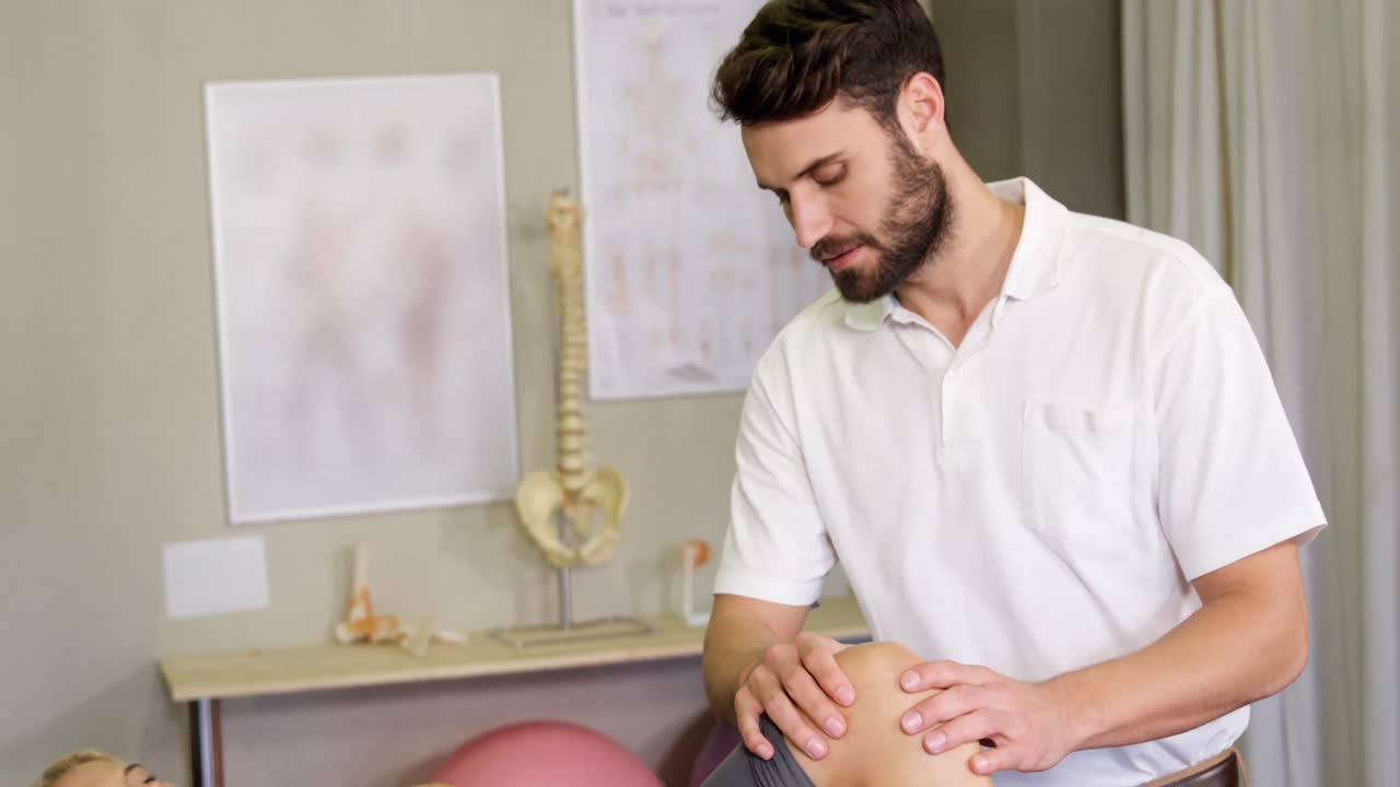 fisioterapeuta masculino dando masaje de rodilla a una paciente femenina