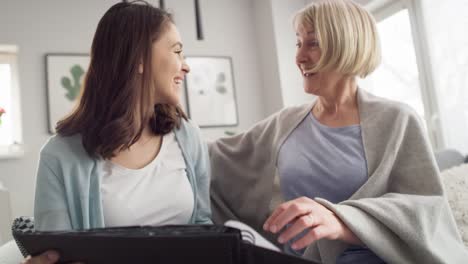 Video-of-happy-mother-and-adult-daughter-looking-photo-album