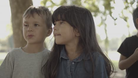 cute boy and girl standing together and looking at something in the park