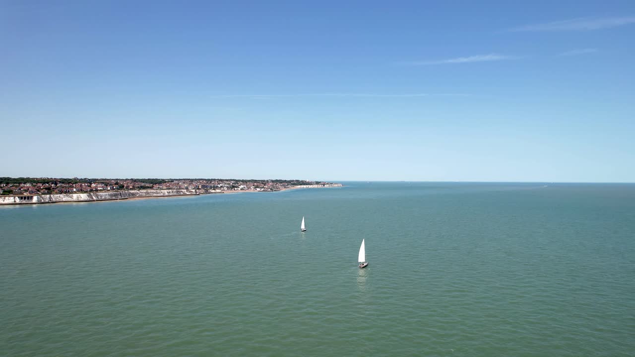 drone volando desde la costa inglesa con dos veleros en primer plano