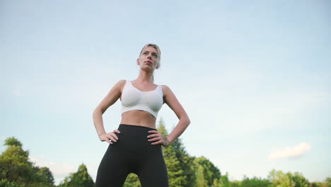 beautiful blonde fitness girl doing side bend exercises outdoors, in the park