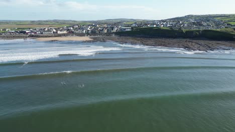 rising aerial shot of surfers waiting on the right wave at lahinch beach ireland