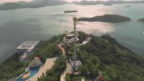 Toma-Aérea-En-órbita-De-La-Torre-Del-Parque-Oceánico-Con-Barcos-Y-La-Isla-Lamma-En-El-Fondo---Hermoso-Paisaje-En-Hong-Kong