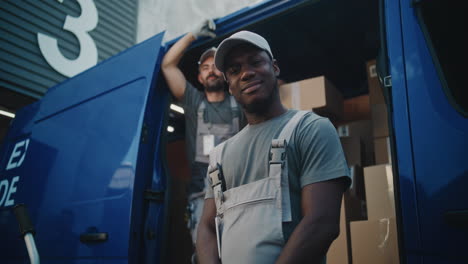 two delivery workers standing by their van filled with packages