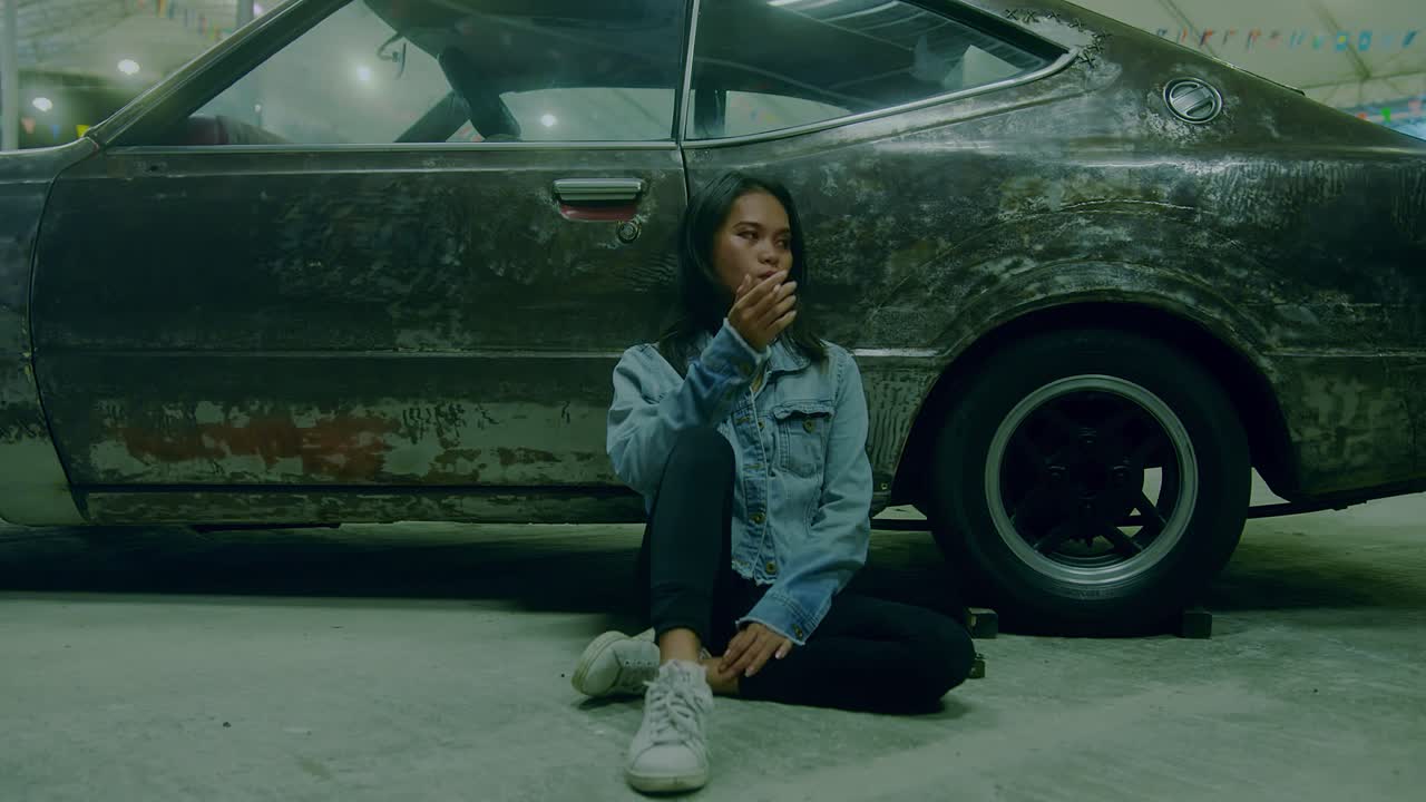 Woman sitting next to a vintage car