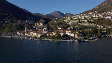 Vista-Aérea-De-La-Pintoresca-Ciudad-Italiana-Junto-Al-Lago-Y-Comuna,-Tavernola-Bergamasca,-Frente-A-Las-Tranquilas-Aguas-Turquesas-Del-Lago-Iseo