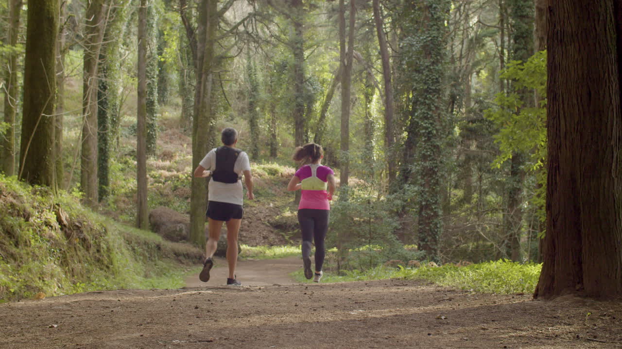 hombre y mujer corriendo de la colina en el bosque