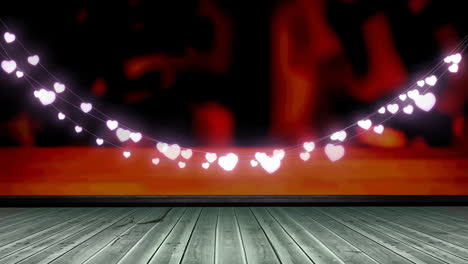 glowing pink heart shaped fairy light decoration hanging over wooden plank