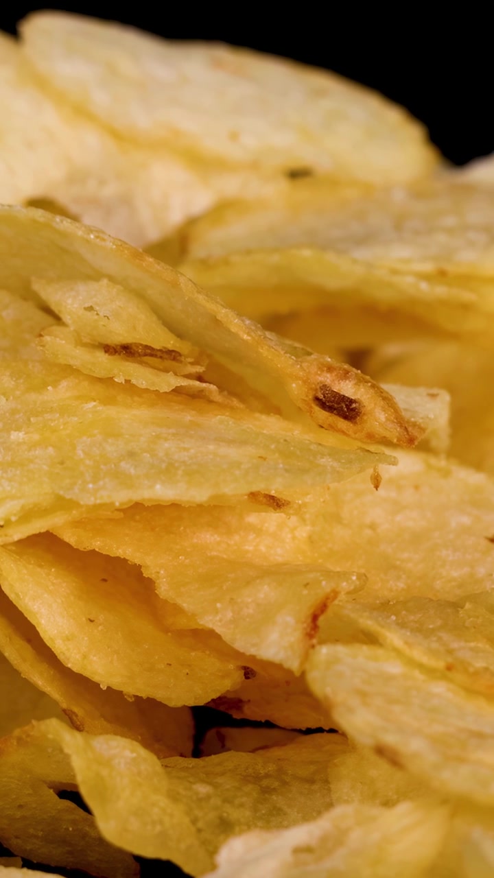 Golden potato chips pile under studio lighting, camera slowly zooms in for detailed close-up