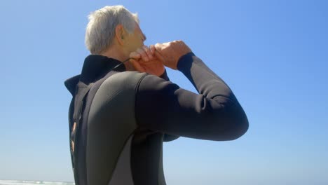 Low-angle-view-of-active-senior-Caucasian-male-surfer-wearing-wet-suit-on-the-beach-4k