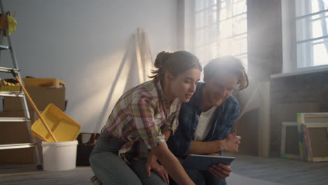 hombre joven con una tableta en el interior. mujer feliz señalando planos en casa.