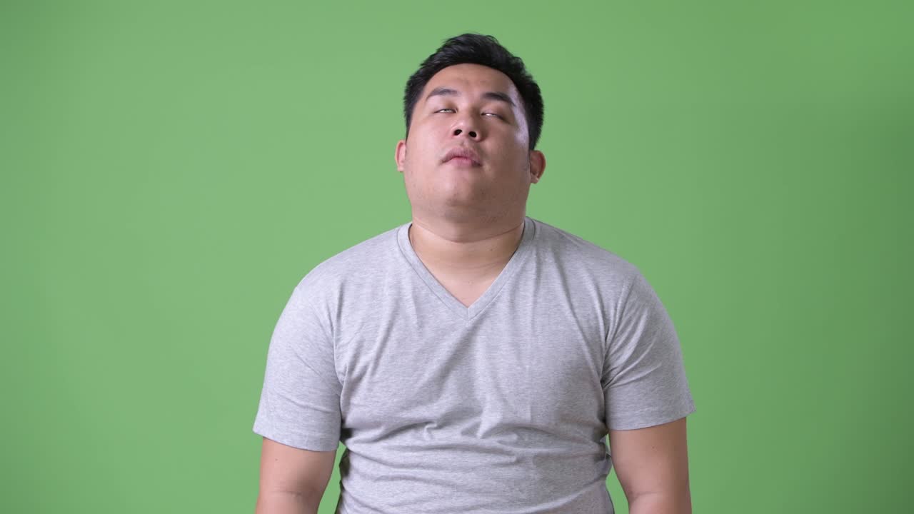 초록색 배경에 젊은 잘생긴 과체중 아시아인