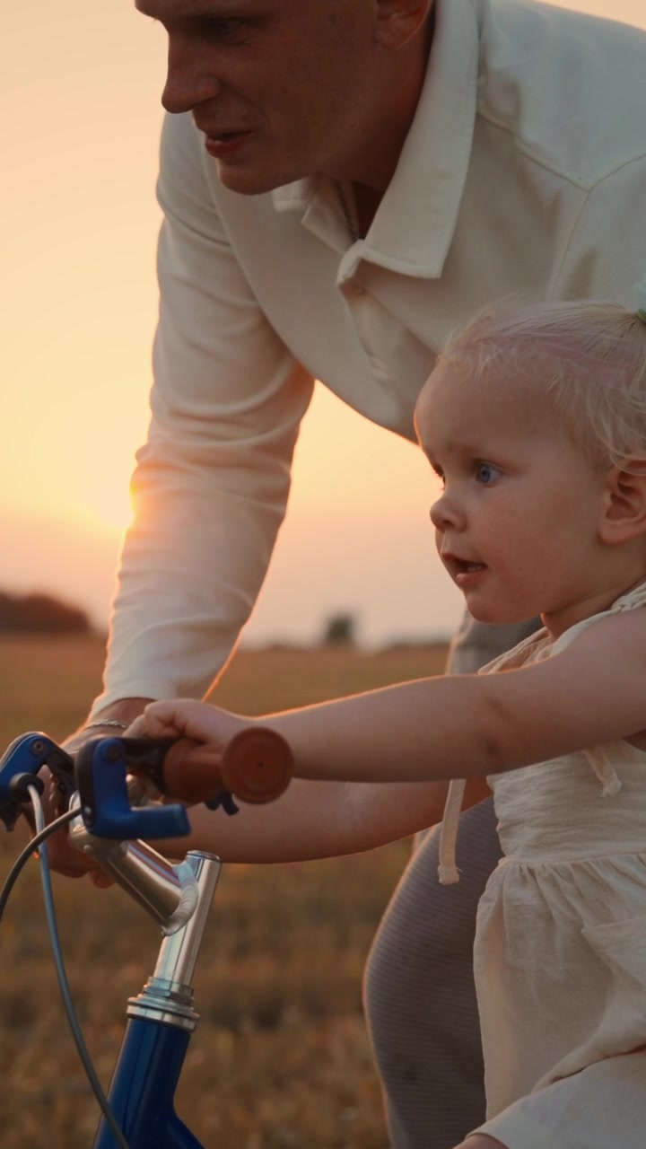 Father Teaching Young Daughter to Ride a Bicycle at Sunset